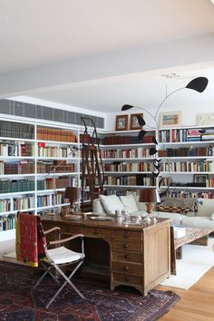 a living room filled with lots of books and furniture next to a book shelf full of books