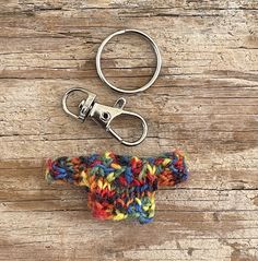 a crocheted keychain is sitting on a wooden table next to a pair of scissors