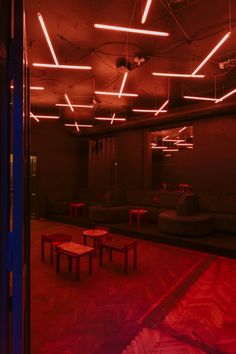 an empty room with tables and benches in the center is lit by red light from overhead lights