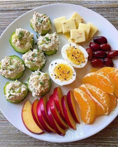 a white plate topped with sliced up fruit and veggies next to deviled eggs