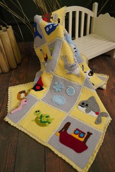 a crocheted blanket with animals on it and a white bench in the background