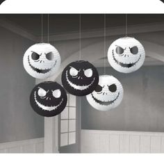 three black and white lanterns with faces hanging from the ceiling in a room decorated for halloween