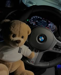 a teddy bear sitting in the driver's seat of a car, next to a steering wheel