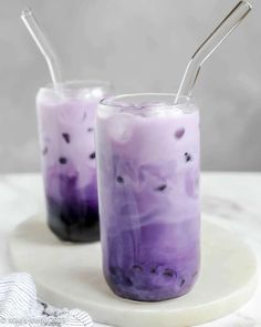 two glasses filled with purple liquid and straws