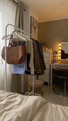 a bedroom with a bed, mirror and clothes rack in the corner next to a window