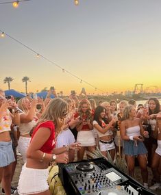 a group of young women standing around a dj's turntable in front of a crowd