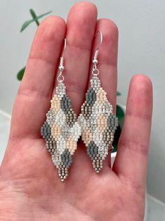 a hand holding a pair of beaded earrings