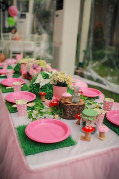 a table set up with pink plates and flowers