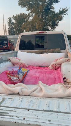 the back end of a white truck with pillows and blankets in it's bed