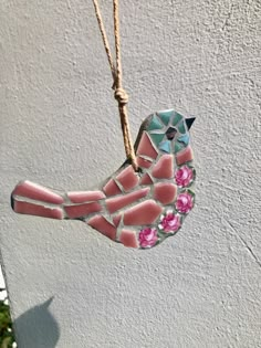 a glass bird ornament hanging from a rope with flowers on it's side