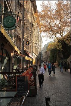 people are walking down the street in front of shops