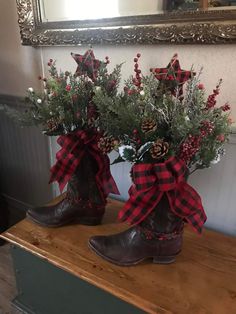 a pair of boots that are sitting on a table with flowers in them and some pine cones