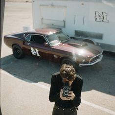 a man holding a camera in front of a car