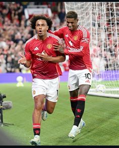 two soccer players are running on the field with their hands in each other's pockets