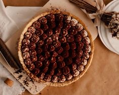 a chocolate pie sitting on top of a table next to plates and utensils