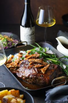 a plate with meat and vegetables next to two bottles of wine