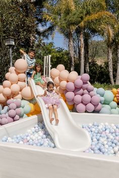 two children on a slide with balloons in the background