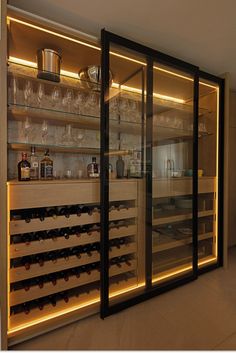 a wine cellar with many bottles and glasses on the shelves in front of glass doors