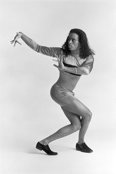 a black and white photo of a woman in tight clothes dancing with her arms outstretched