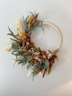 a wreath with dried flowers and leaves hanging on the wall