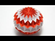 an origami ball with red, white and grey designs on the top is shown