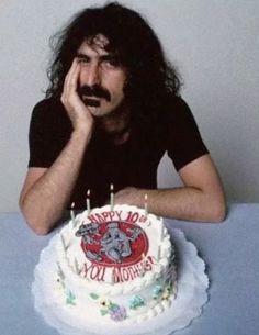 a man sitting in front of a cake with candles on it