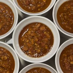 several bowls filled with chili and beans on top of a table