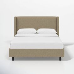 an upholstered bed with white pillows and linens on the headboard is shown