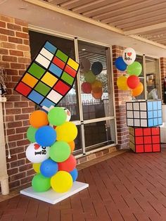 balloons and cubes are on display in front of a brick building with large windows