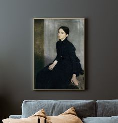 a portrait of a woman sitting on top of a couch in front of a gray wall