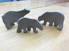 three cement polar bears sitting on top of a wooden table