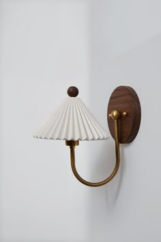 a wall light with a white shade hanging from it's side on the wall