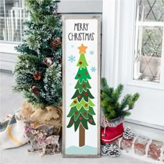 a wooden sign with a christmas tree painted on it next to a potted plant