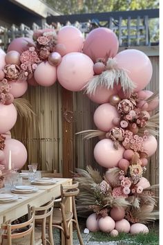 a table with pink balloons and flowers on it