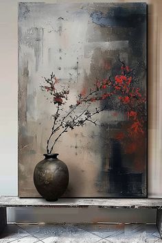 a vase with red flowers sitting on top of a wooden table next to a painting