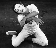 a man sitting on the ground with his head down and hands behind his back as he stretches