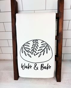 a white towel with black lettering on it sitting next to a wooden stand holding a loaf of bread