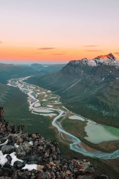 the sun is setting over some mountains and rivers in the distance, with snow on the ground