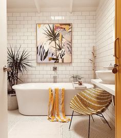 a bath room with a tub a sink and a painting