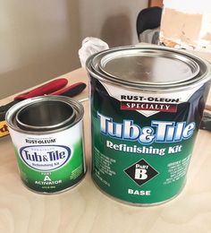 two cans of paint sitting on top of a wooden table next to scissors and pliers