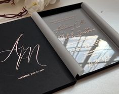 the inside of an open black and white wedding album with gold foil lettering on it