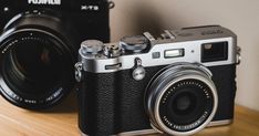 a camera sitting on top of a wooden table next to another camera and its lens