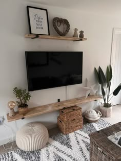 a flat screen tv sitting on top of a wooden shelf next to a potted plant