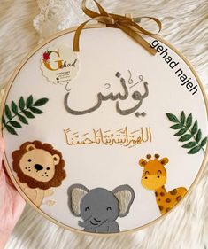 a hand holding a embroidery kit with animals and giraffes on it's side