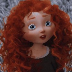 a close up of a doll with red hair and big blue eyes in the snow