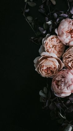 a bunch of pink flowers sitting on top of a black table next to green leaves