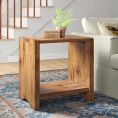 a small wooden table with a potted plant on it in front of a stair case