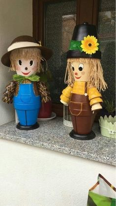 two little scarecrows sitting on top of a window sill