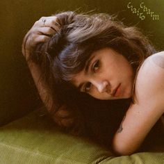 a woman laying on top of a green couch next to a wall with writing on it