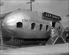 a large silver boat sitting on top of a sidewalk next to a building and stairs